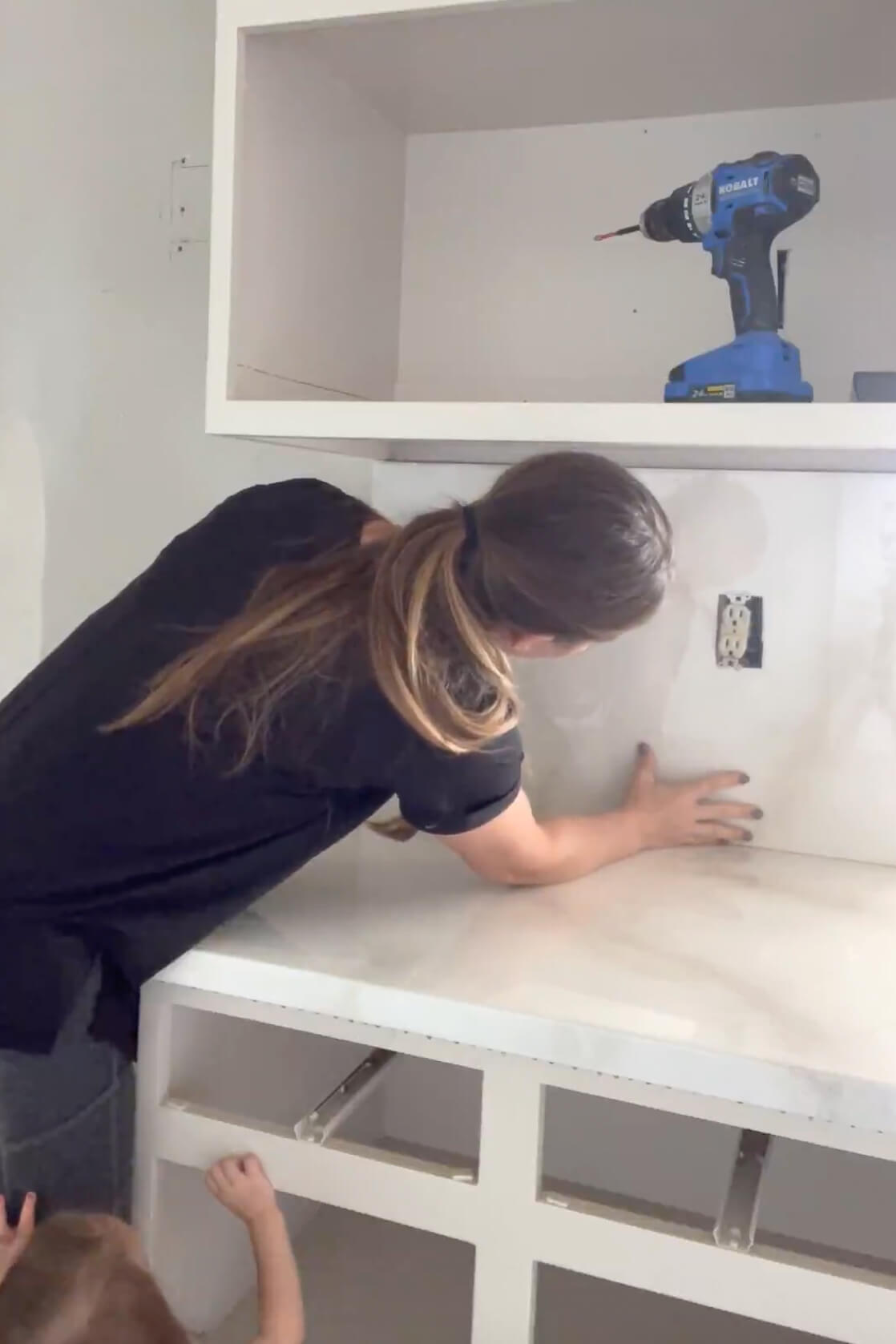 Attaching a faux marble kitchen backsplash using liquid nails.